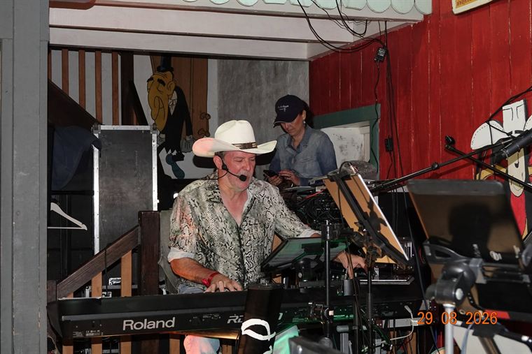 Muzikant met witte cowboyhoed en headsetmicrofoon achter de keyboards op het festival