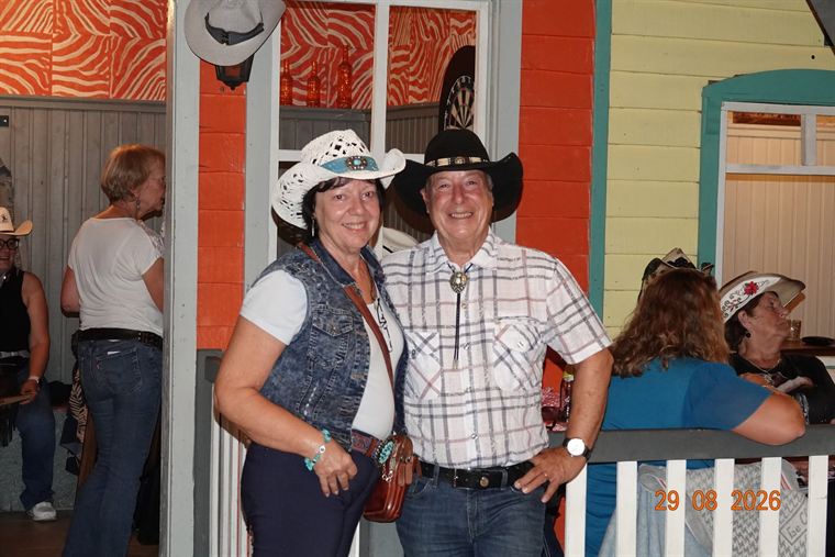 Koppel met cowboyhoeden poserend op het terras van de saloon